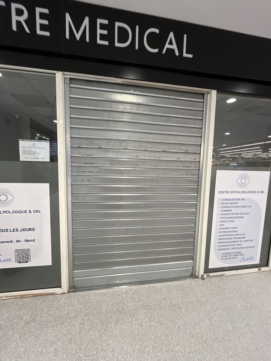 Closed micro-perforated shutter protecting a medical centre entrance – repair in Cergy
