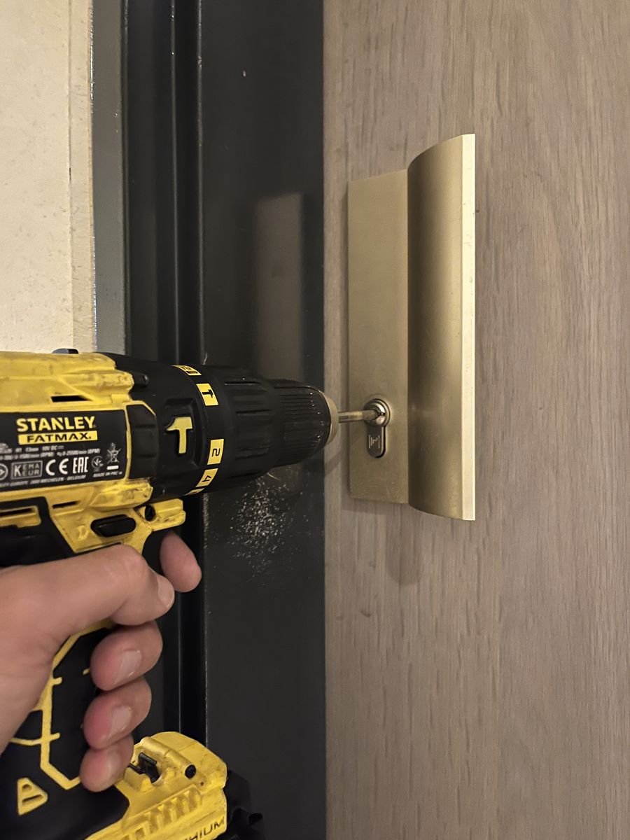 Serrurier fixant un cylindre neuf à la visseuse sur une porte de bureau – serrurier à Boissise-la-Bertrand