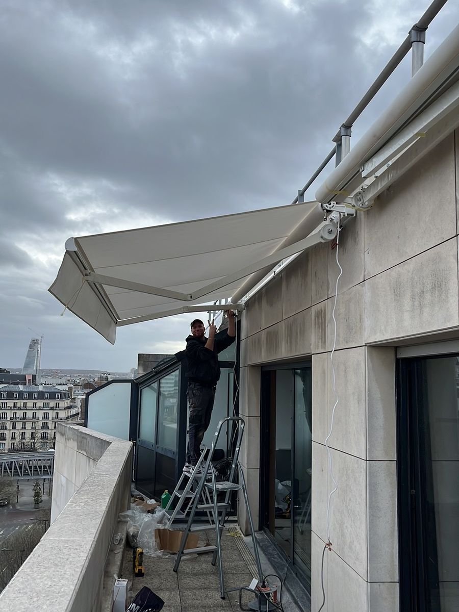 DRM Paris technician fixing a cassette awning on an upper-floor terrace – awning in Berville